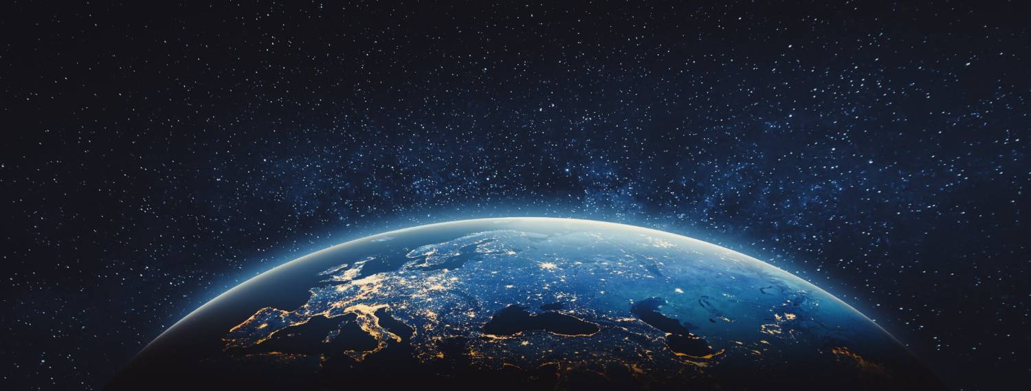 Earth from space at night showing city lights and cloud formations against starry sky