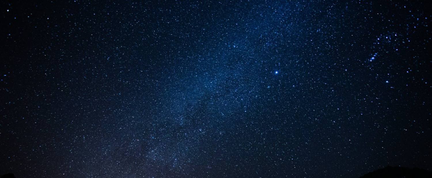 Deep space night sky filled with countless stars and the Milky Way galaxy stretching across darkness